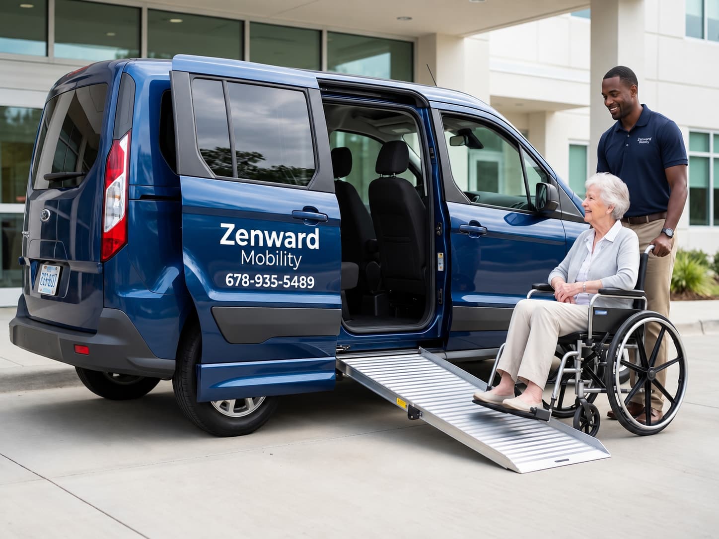 A Zenward Mobility staff member standing with an older passenger seated in a wheelchair at the foot of the deployed side ramp of a navy Zenward Mobility van, outside a medical building